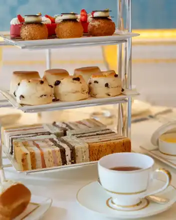 Food type: Tiered stand with sandwiches, scones and pastries beside a cup of tea